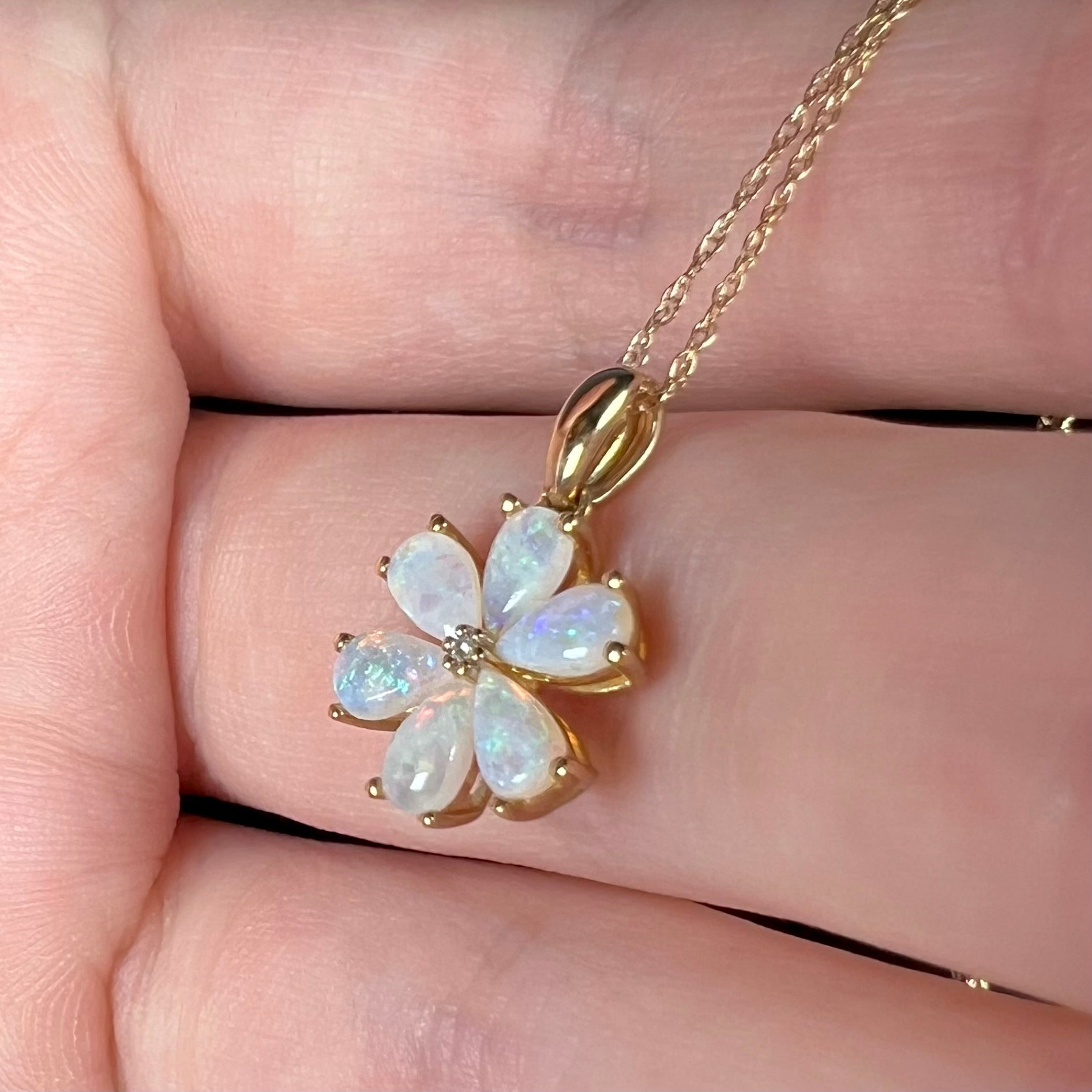 10k gold opal flower necklace on gold chain, resting in hand shown close-up