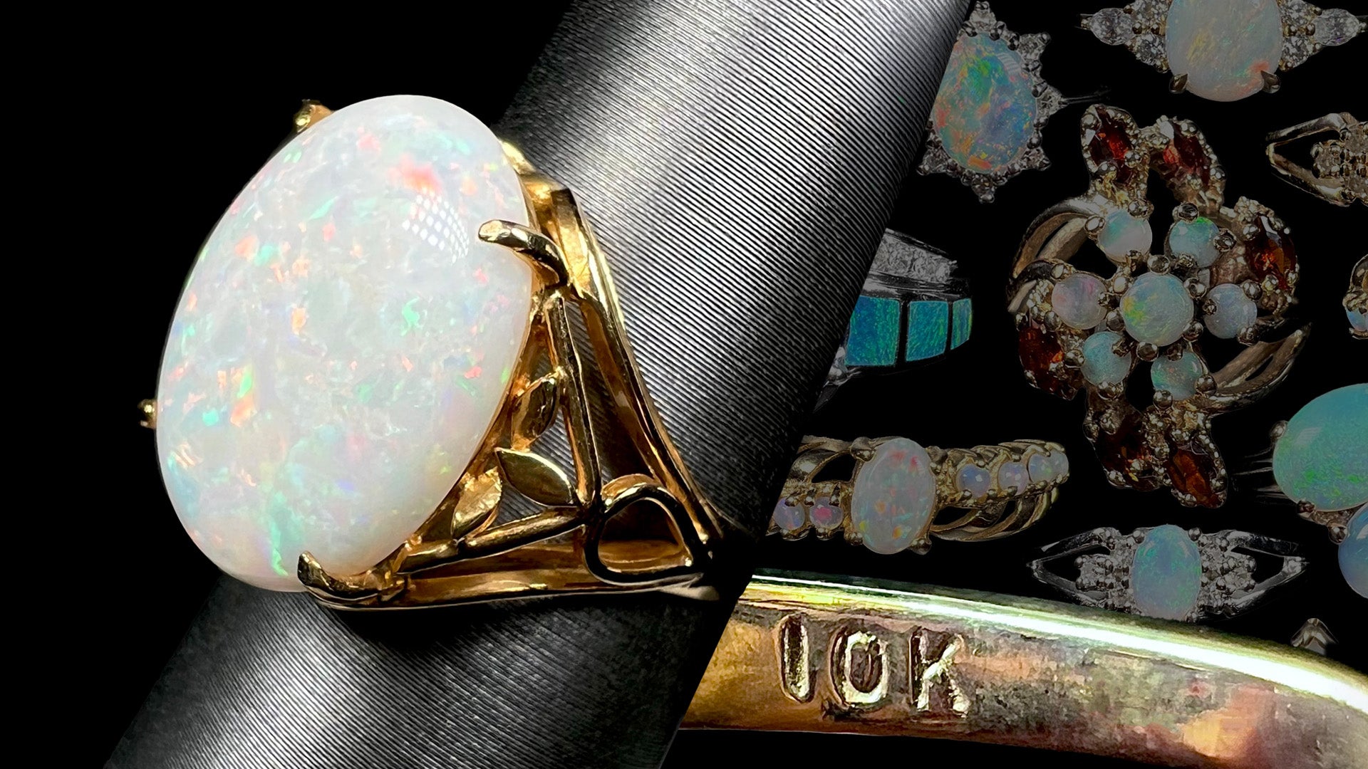 Large 10k gold opal ring on ring display shown from angle in front of faded gold opal rings with inside of ring's shank with "10K" hallmark stamp in focus.