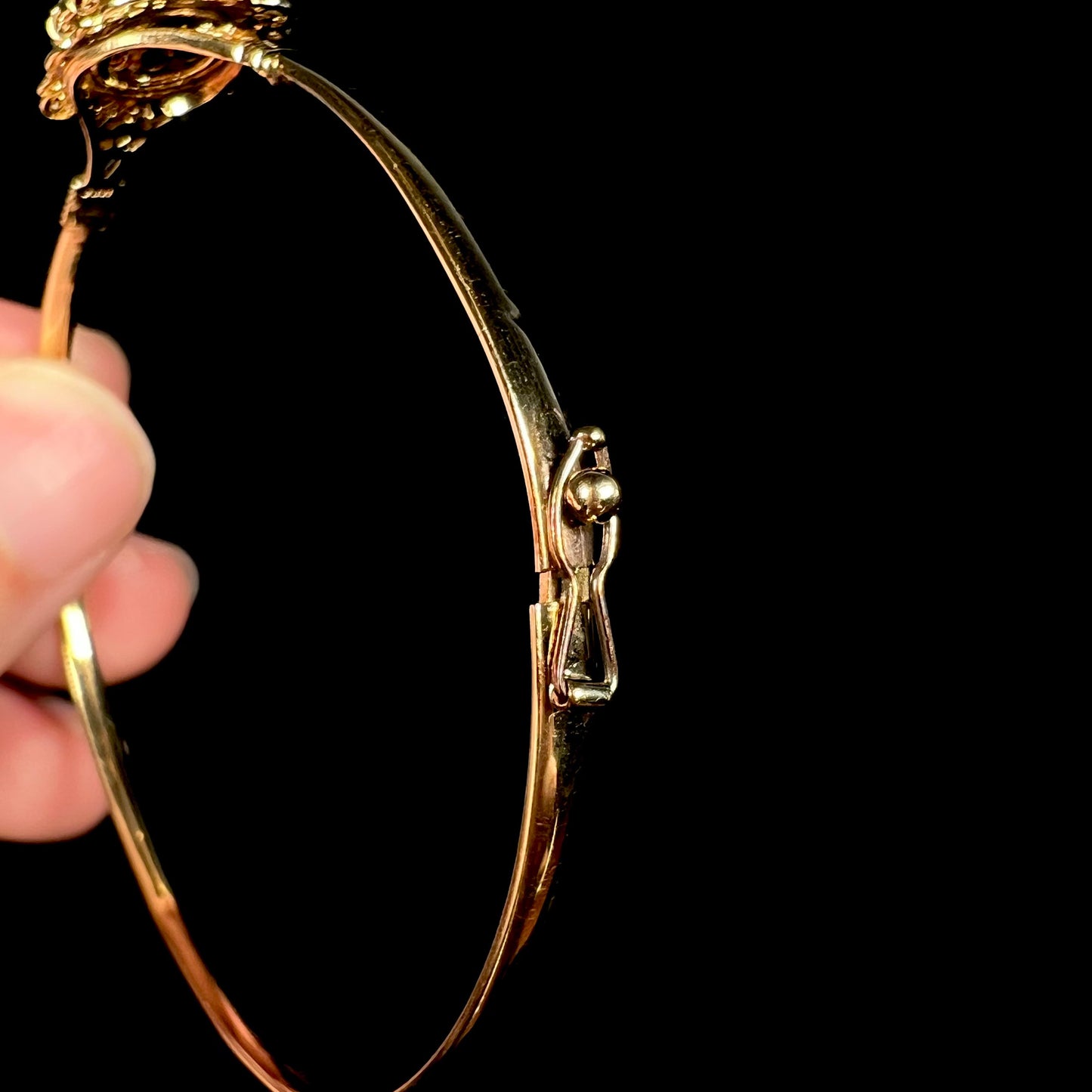 A vintage yellow gold opal bangle bracelet showing the single-latch locking mechanism close-up.