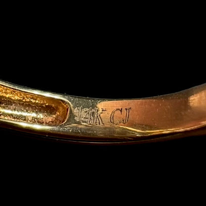 Close-up of the inside of a gold ring's shank, showing the laser-etched hallmark stamps "14K" and "CJ", denoting designer Cirari Jewels.