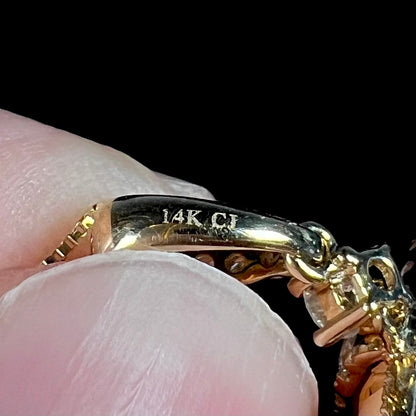 Close-up of a gold pendant's bail with the hallmark stamps "14K" and "CJ", attributed to designer, Cirari Jewels.
