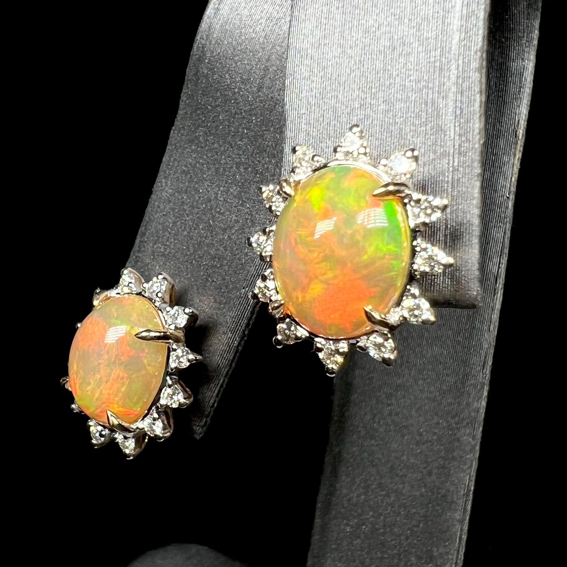 Pair of oval shaped 14k gold Ethiopian opal and diamond earrings on earring display
