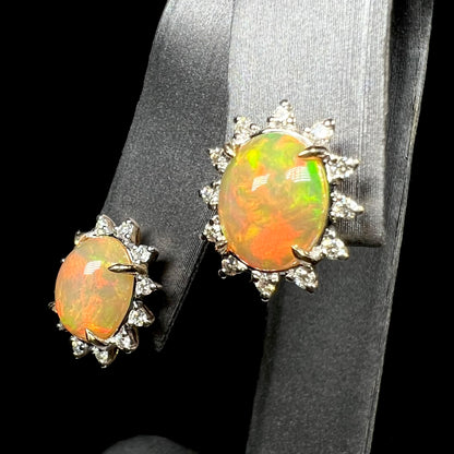 Pair of oval shaped 14k gold Ethiopian opal and diamond earrings on earring display