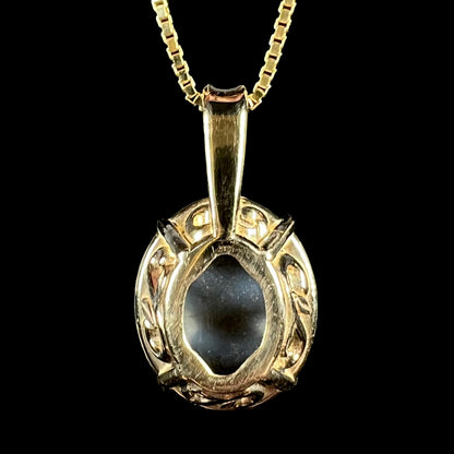 Back side of 14k yellow gold filigree basket pendant set with black opal; the black opal's natural potch backing visible