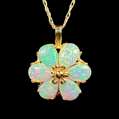 Close-up of 14k gold flower pendant set with six pear shaped lab-created opals, shown on gold chain