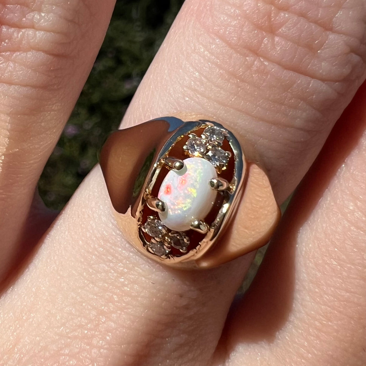 Sunlit close-up of vintage Mid-Century modern opal and diamond ring with polished 14k gold dome design, worn on finger