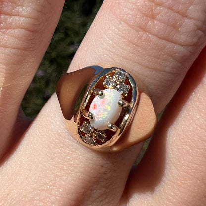 Sunlit close-up of vintage Mid-Century modern opal and diamond ring with polished 14k gold dome design, worn on finger