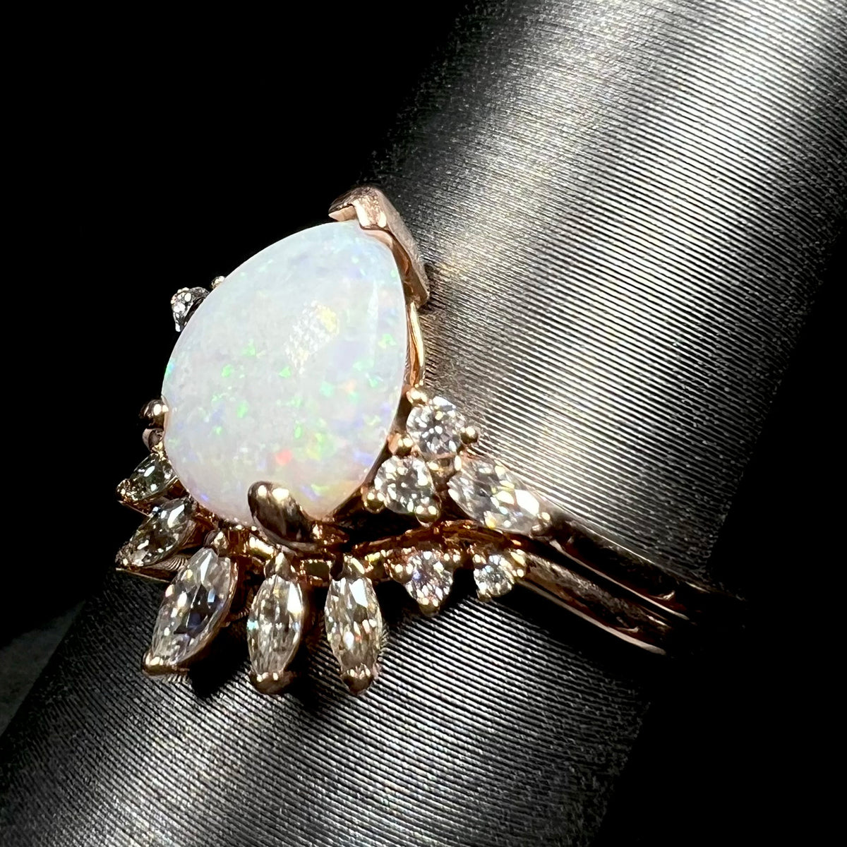 14k rose gold pear shaped opal and moissanite engagement and wedding ring set on display