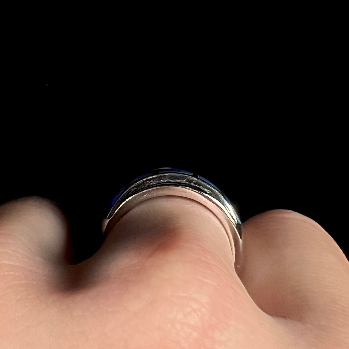 Side profile gallery view of a 14k white gold ring, worn on a hand; the blue opal inlay is flush along the ring's surface, barely in view