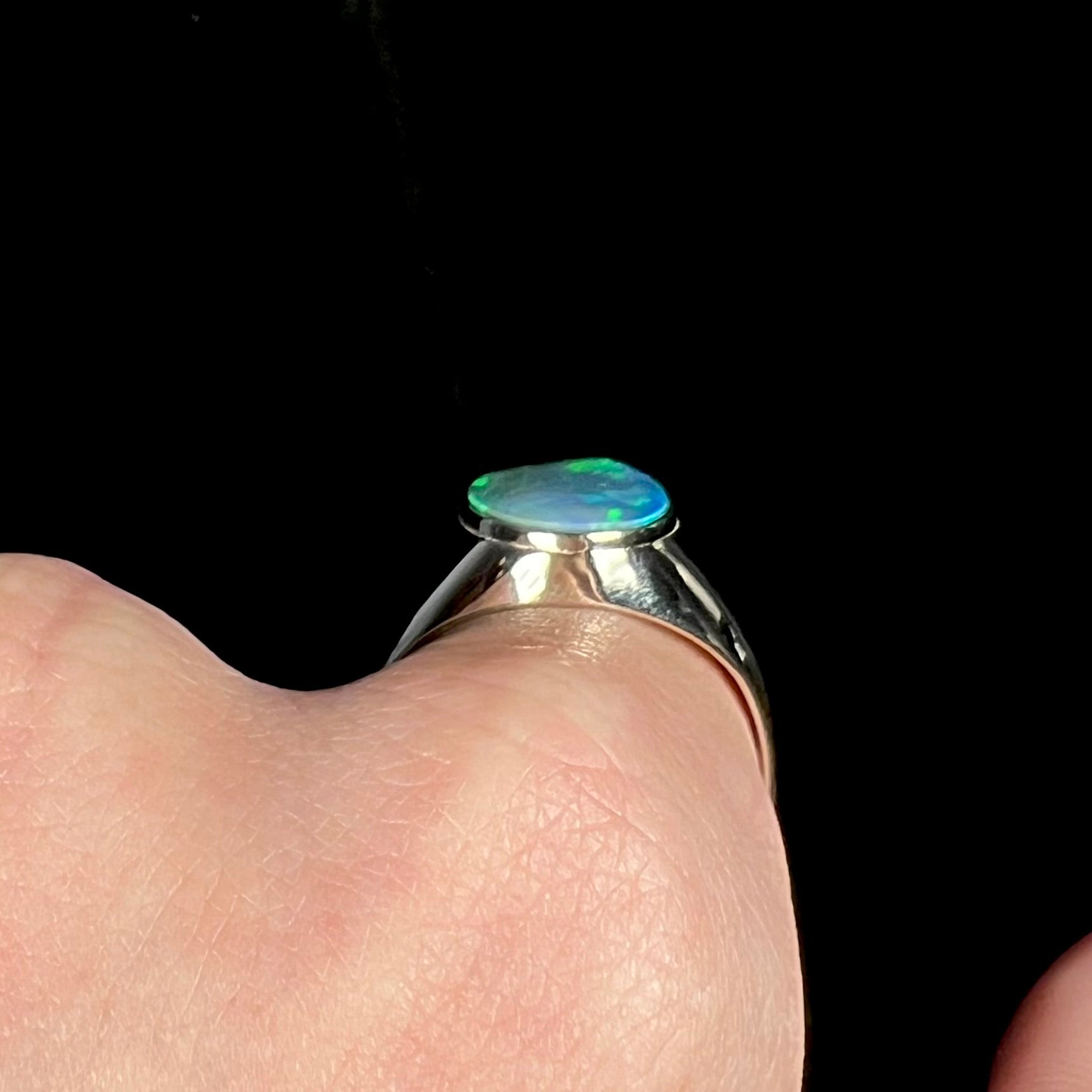 Side gallery profile view of a 14k white gold opal men's ring, worn on hand