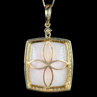 Back side of a delicate 14k yellow gold pink Peruvian opal pendant by designer, Cirari, shown against black backdrop.  The back of the pendant has a four-petal floral motif.