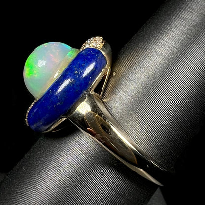 A lapis lazuli opal ring shown from the side view close-up on a ring display.  The ring's 14k yellow gold shank and carved lapis halo are in focus.