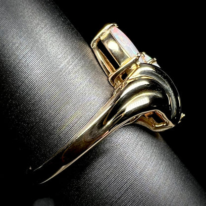 Side view of a 14k yellow gold Modernist-style opal ring on a ring display.