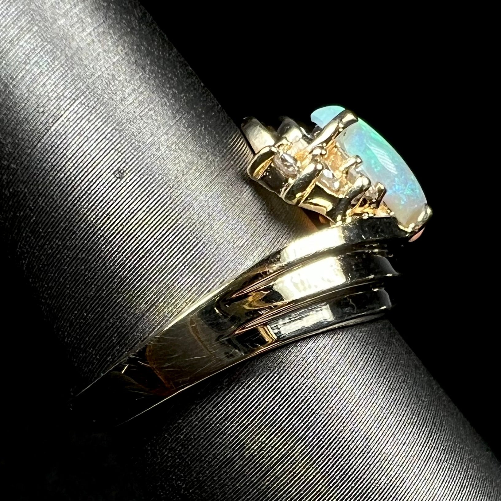 Side view of 14k yellow gold opal ring on ring display, focused on one side of ring's shank