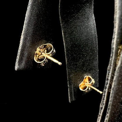 Back side of 14k yellow gold push-back earrings on earring display showing gold posts