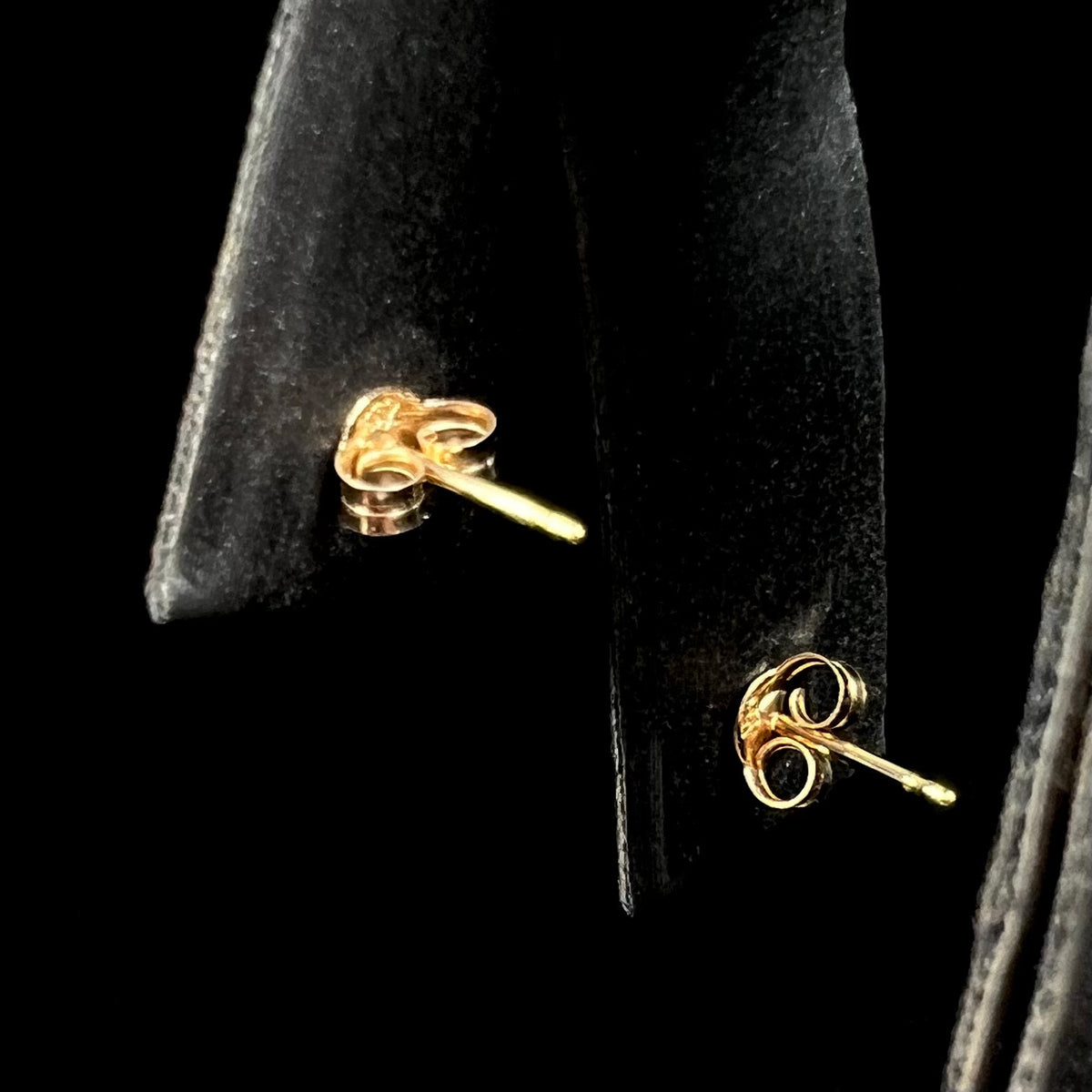 Back side of 14k yellow gold push-back earrings with butterfly backs on earring display