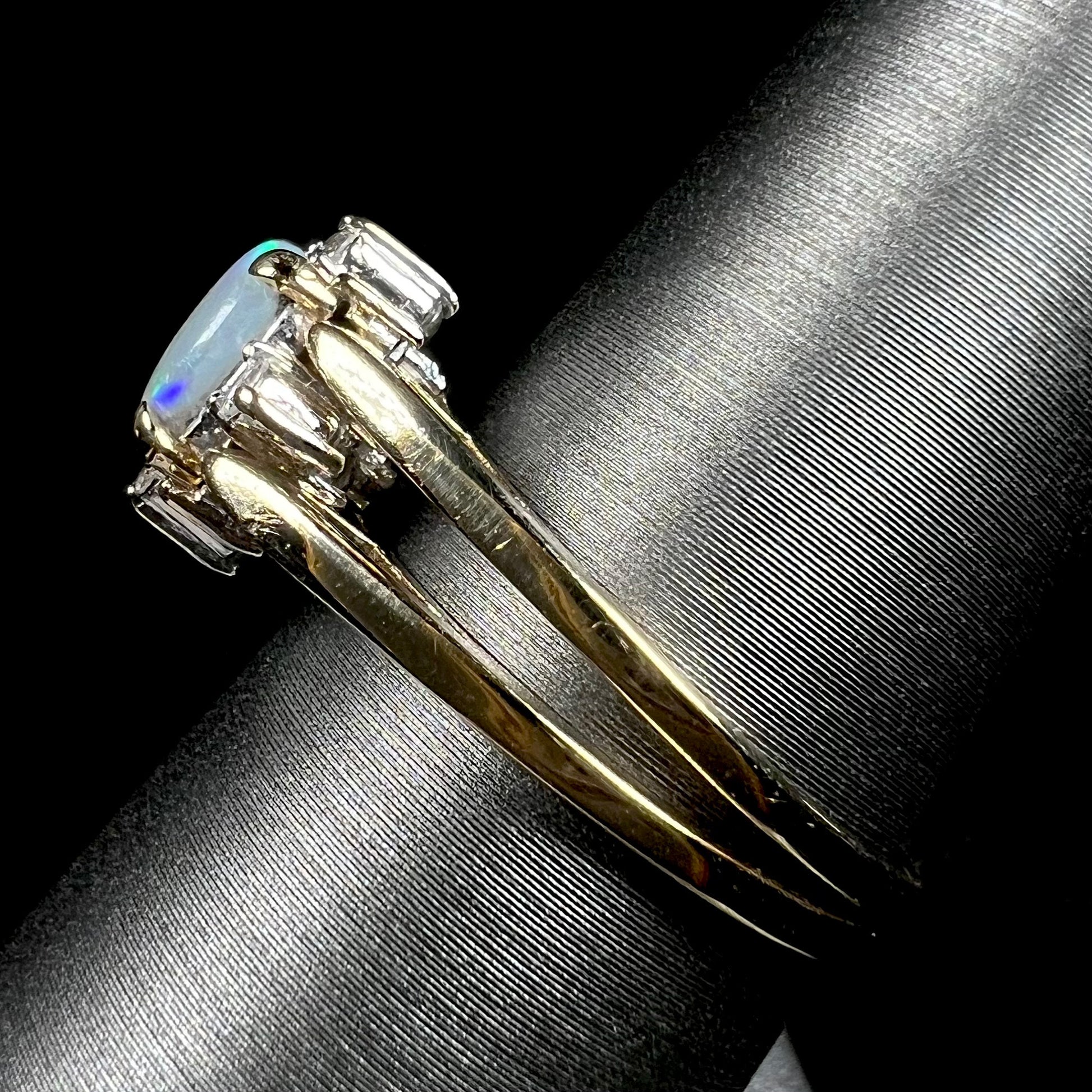Side view of 14k yellow gold reversible opal ring on ring display; the ring's two shanks are in focus