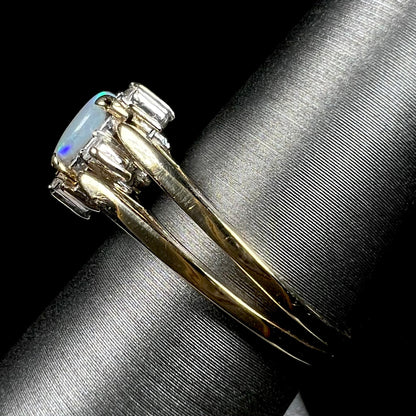 Side view of 14k yellow gold reversible opal ring on ring display; the ring's two shanks are in focus