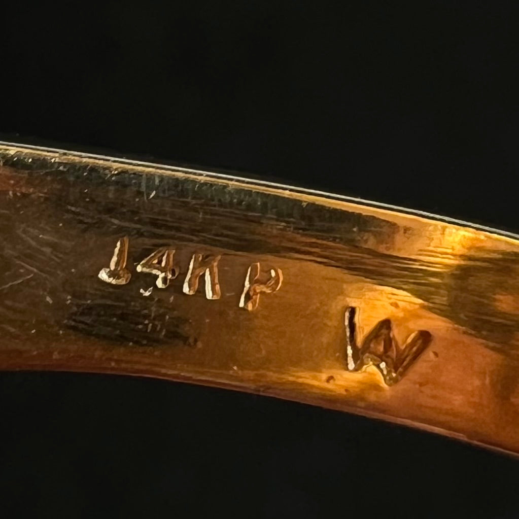 Close-up of the inside of a vintage 1980s gold opal ring's shank showing hallmark stamps "14KP" and "W", denoting 14k gold plumb and the unknown maker's mark