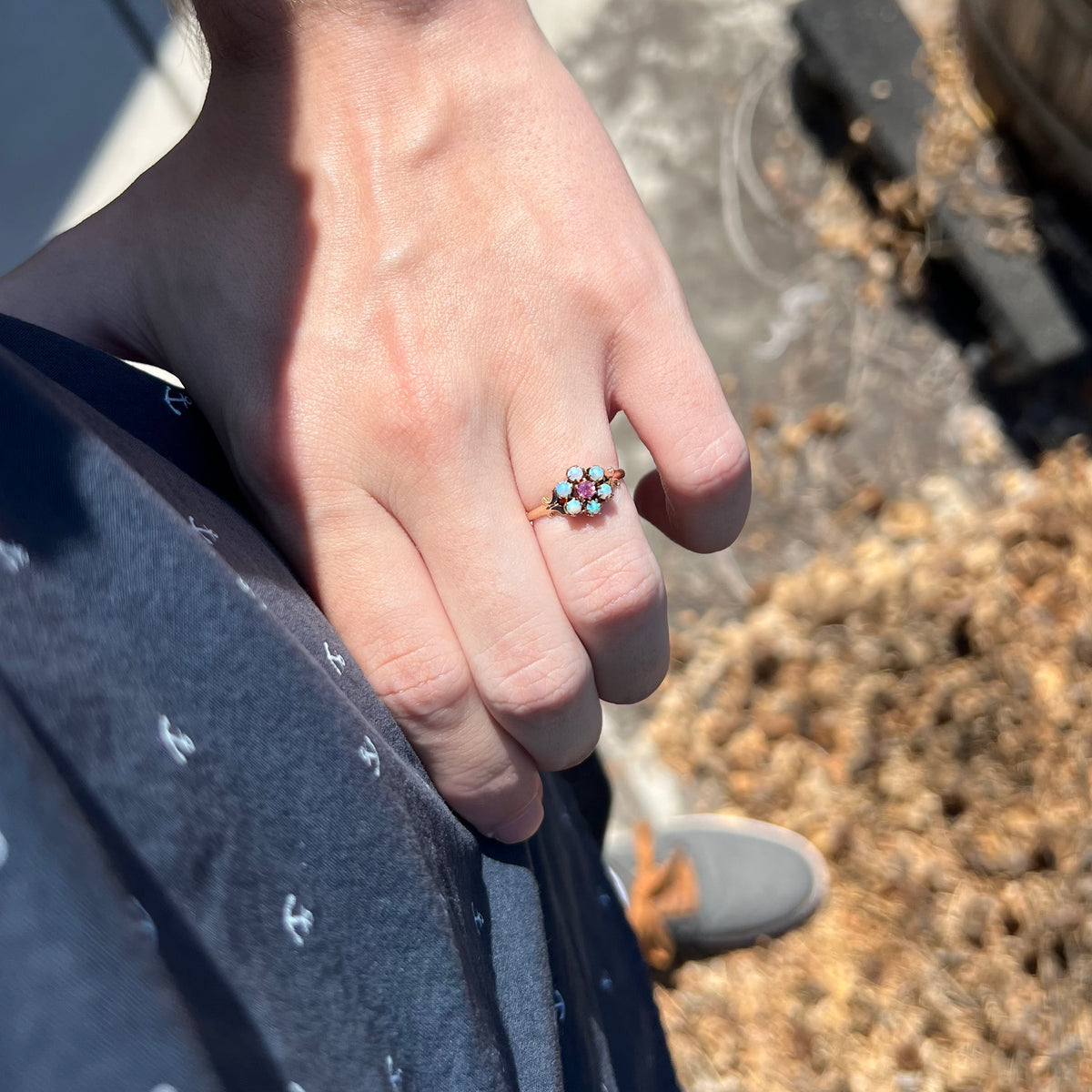 Close-up of person resting hand on hip in sunlight wearing 1880s era women's Hungarian opal and pink tourmaline ring
