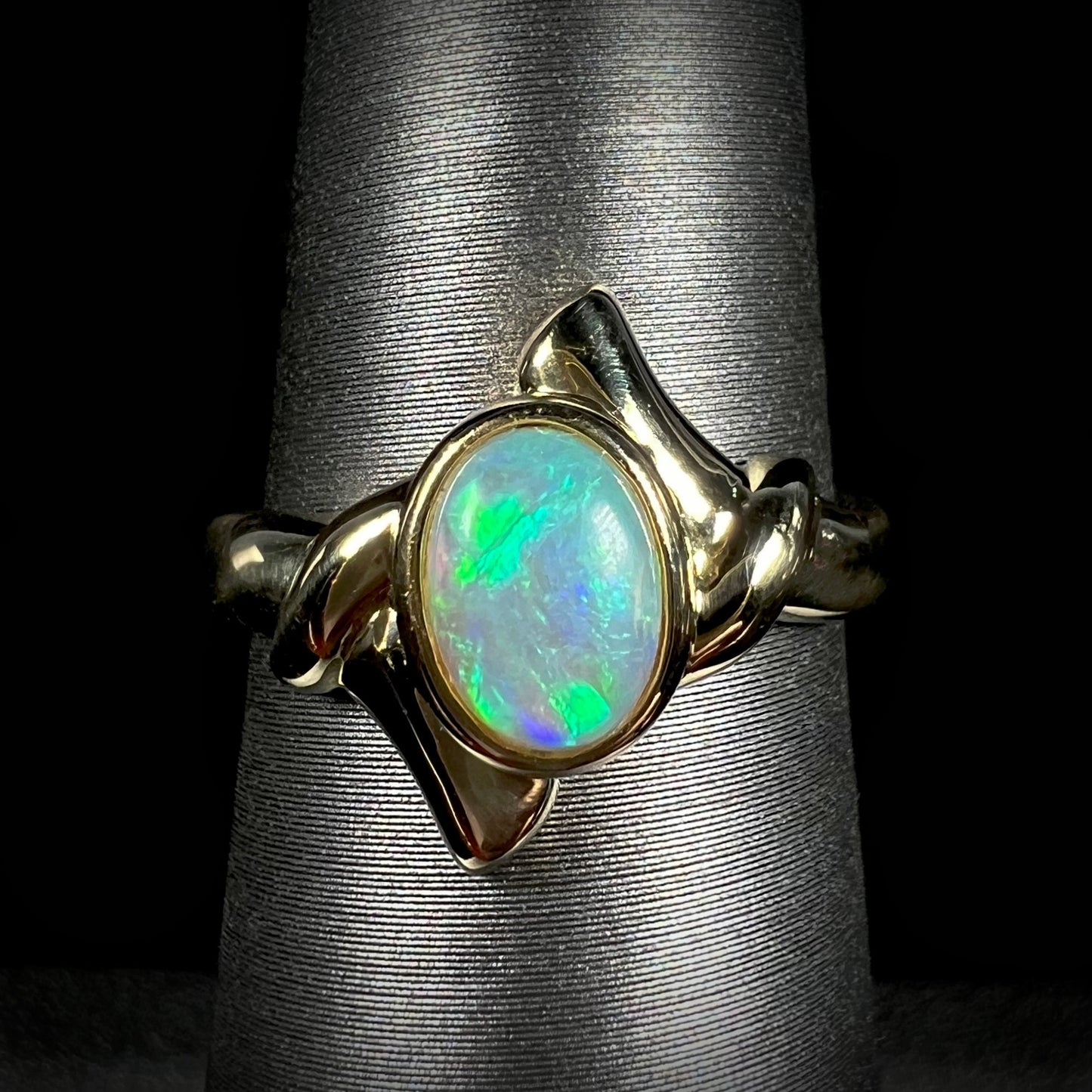 An 18k gold crystal opal engagement ring.  The opal has green and blue color play.