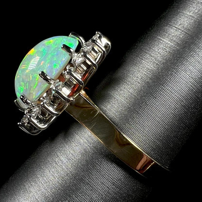 A side-angle view of a 4.30ct Lightning Ridge fire opal engagement ring in 18k gold.  The opal's green fire is visible, with the gold shank in focus.