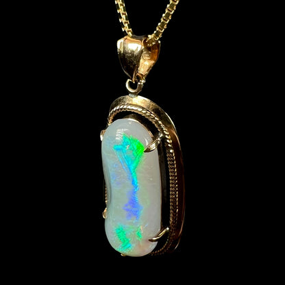 An angled macro shot of an 18k gold Lightning Ridge opal necklace, highlighting the ridge’s bright blue and green flashes.