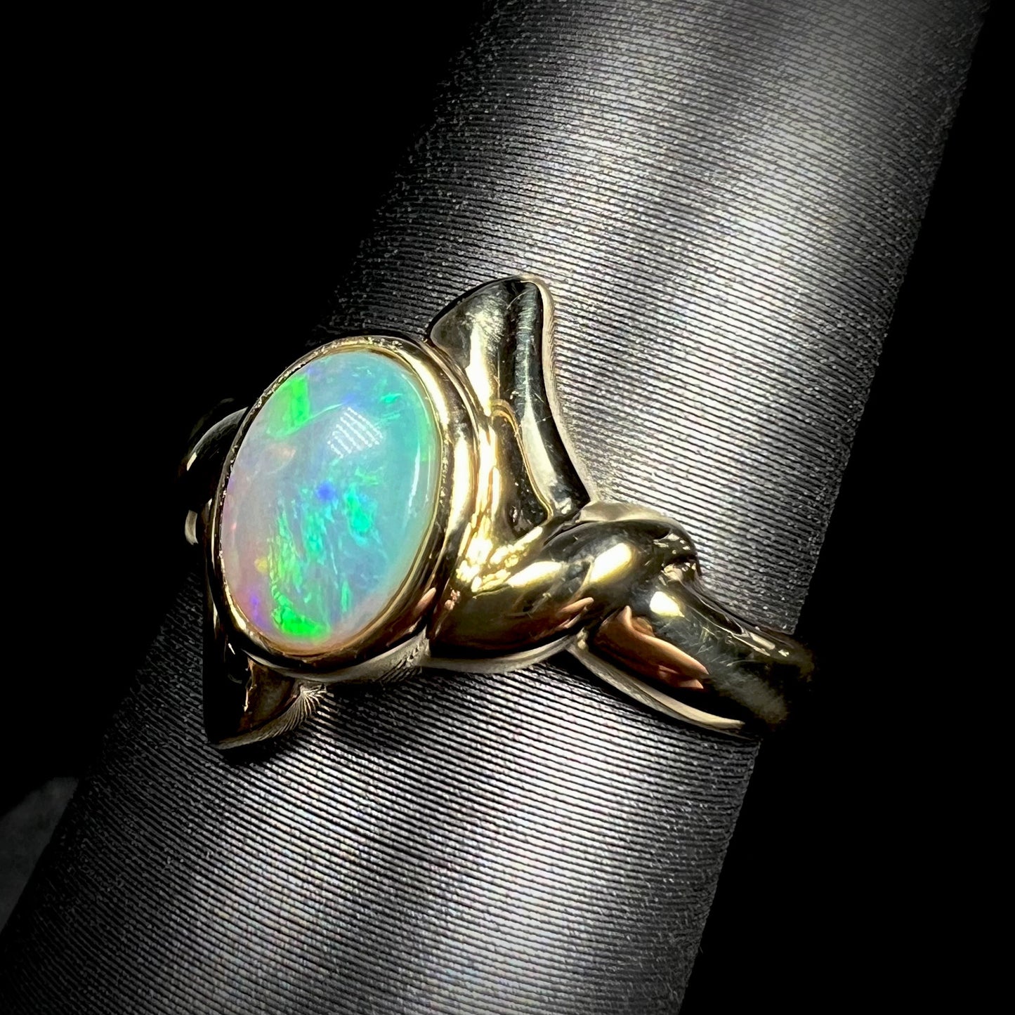 An 18 karat yellow gold opal engagement ring.  The ring is a smooth, dainty solitaire design.