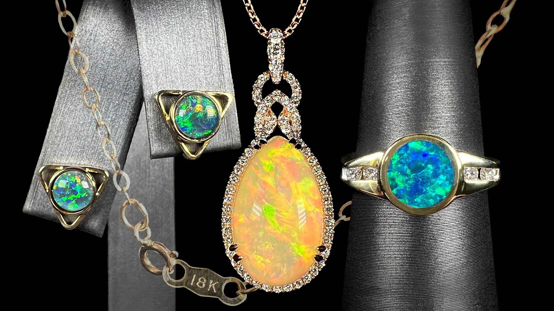 18k gold opal jewelry shown on displays in front of black background with chain stamped "18K".  Yellow gold earrings and ring are shown on each side of rose gold opal necklace.
