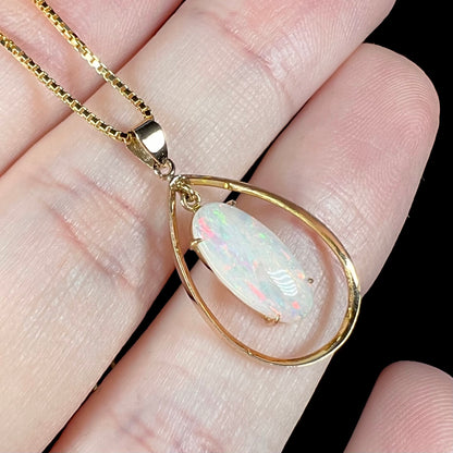 Angled macro shot of an 18k gold opal necklace, displaying pink-striped flashes within the opal’s play-of-color.