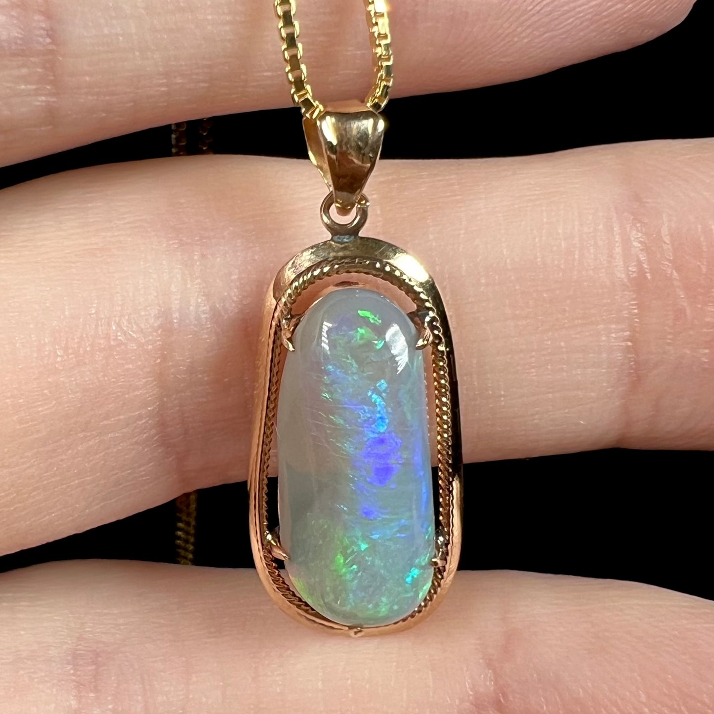 Macro view of an 18k gold Lightning Ridge opal necklace, with only faint blue and green flashes visible.