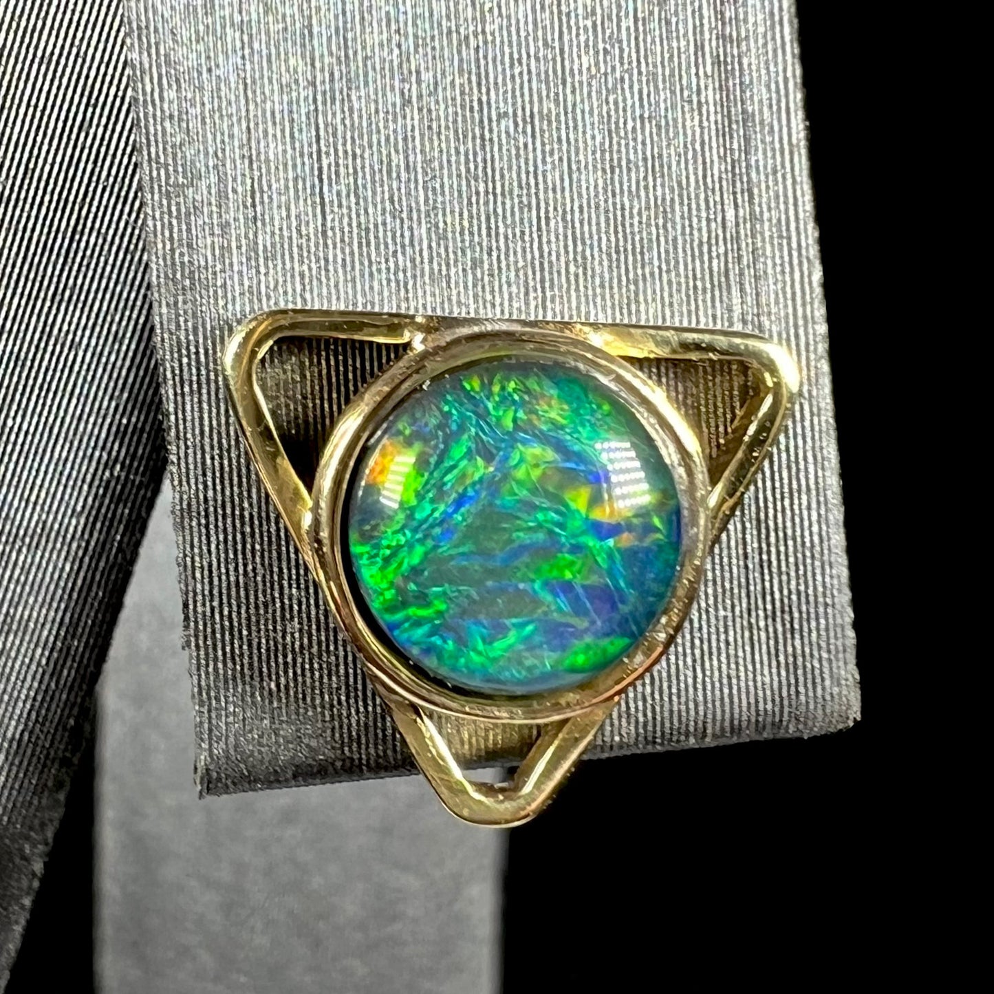 One 18k gold opal stud earring, shaped like a triangle, shown from the front up close.
