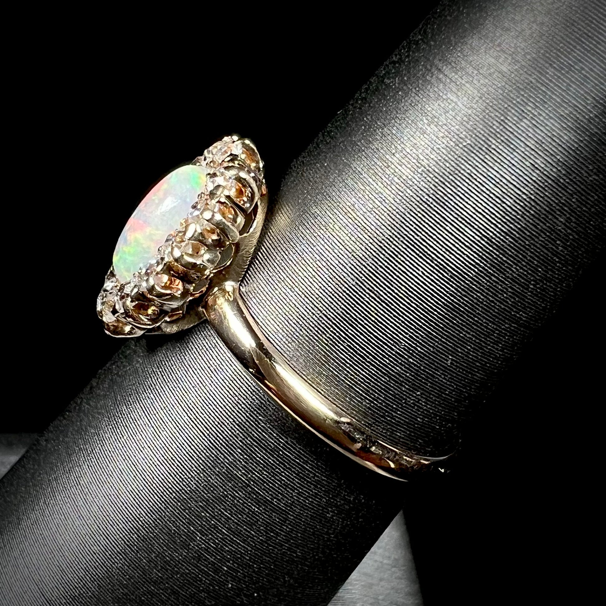 The side angle of an Edwardian opal and diamond halo ring.  The ring is 18 karat yellow gold.