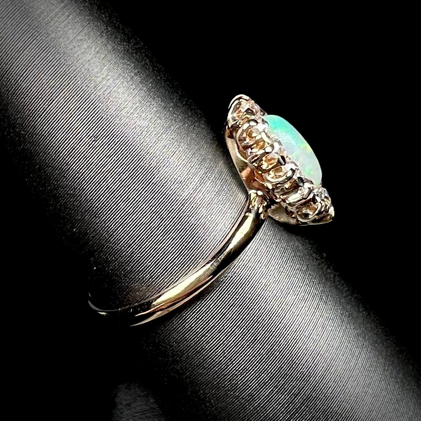 The side of an 18 karat yellow gold opal and diamond ring.  The ring is Edwardian style and set with European Cut diamonds.