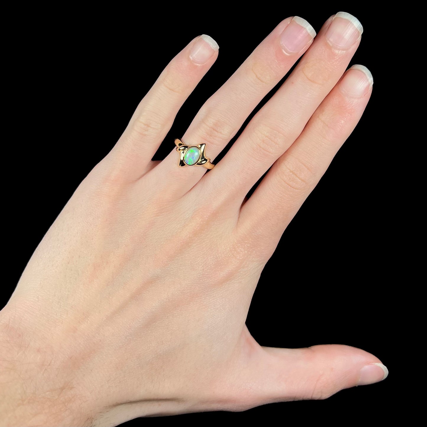 An 18 karat gold opal solitaire engagement ring.  The opal has green color play.