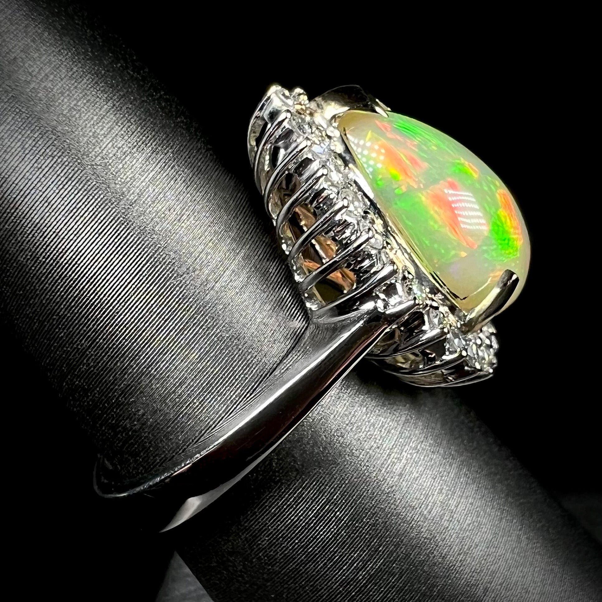 Side view of an 18k white gold fire opal and diamond halo ring, focused on the ring's shank and basket set design.
