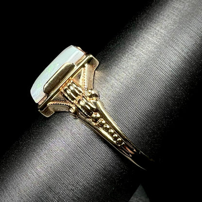 Side view of a c.1920s era gold opal ring on a ring display, the ring's ornate Art Deco-style shank in focus