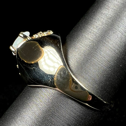 Side view of a 1960s Mid-Century era 14k gold opal ring with polished dome design, shown on ring display