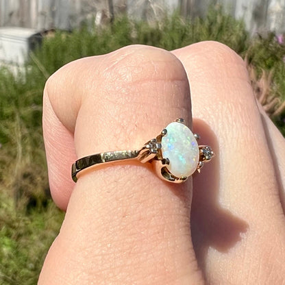 A dainty, 1960's style opal and diamond engagement ring.  The ring is prong-set and yellow gold.
