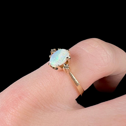 A dainty, 1960's style opal and diamond engagement ring.  The ring is prong-set and yellow gold.