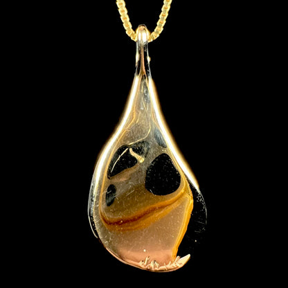 Back side of c.1980s era 14k gold pendant.  The hallmark stamps "J.D" and "14K" are visible at the bottom of the pendant.