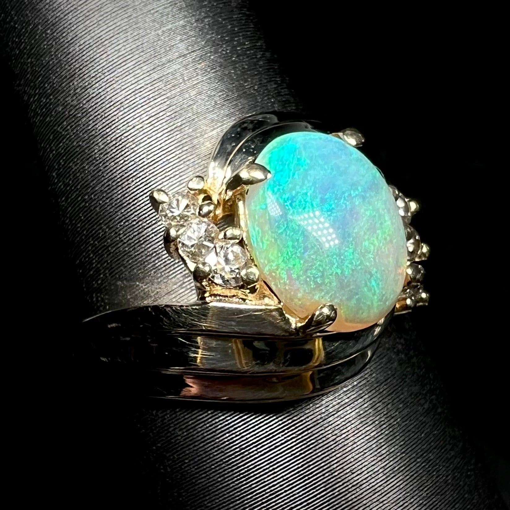 1980s era Modernist opal and diamond ring in 14k gold with bypass shank design, shown from angle on ring display