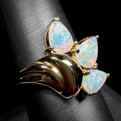 Angled view of a 1980s-era Modernist three-stone Australian opal ring on a ring display.  A domed gold design element is in focus.