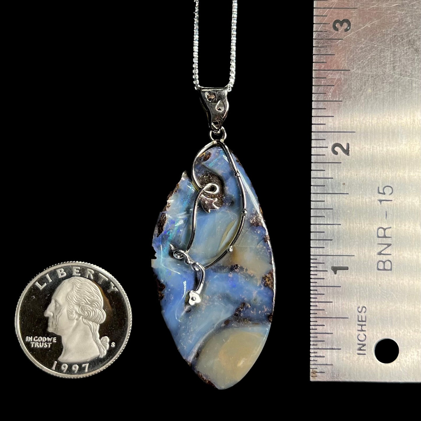 A 2.25 inch long blue Australian boulder opal necklace in sterling silver, shown next to a quarter coin and ruler.