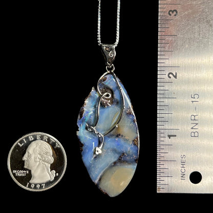 A 2.25 inch long blue Australian boulder opal necklace in sterling silver, shown next to a quarter coin and ruler.