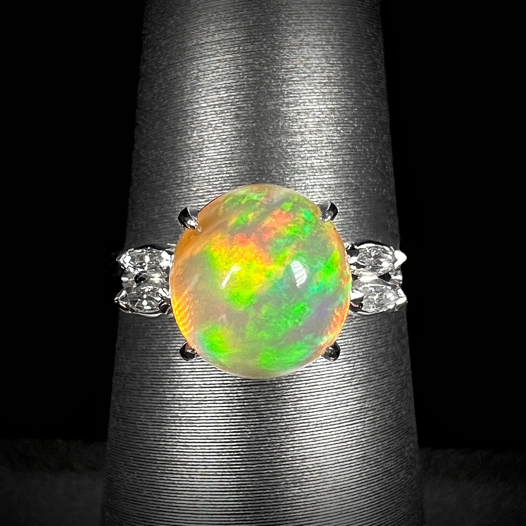 A 2.28ct Mexican fire opal engagement ring in platinum, featuring a round opal with vivid red and green fire, accented by marquise-cut diamonds.