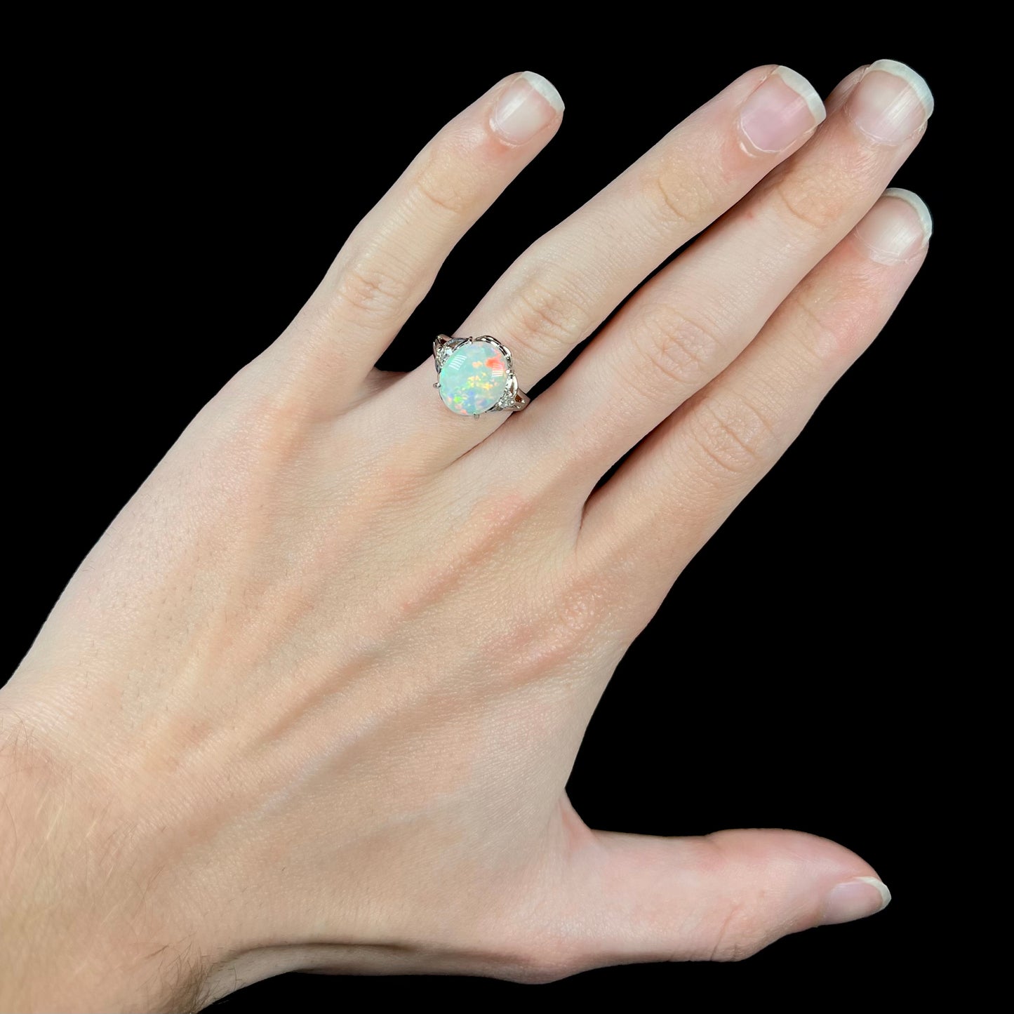 A Japanese-made 2.36ct opal and diamond platinum ring worn on a hand.