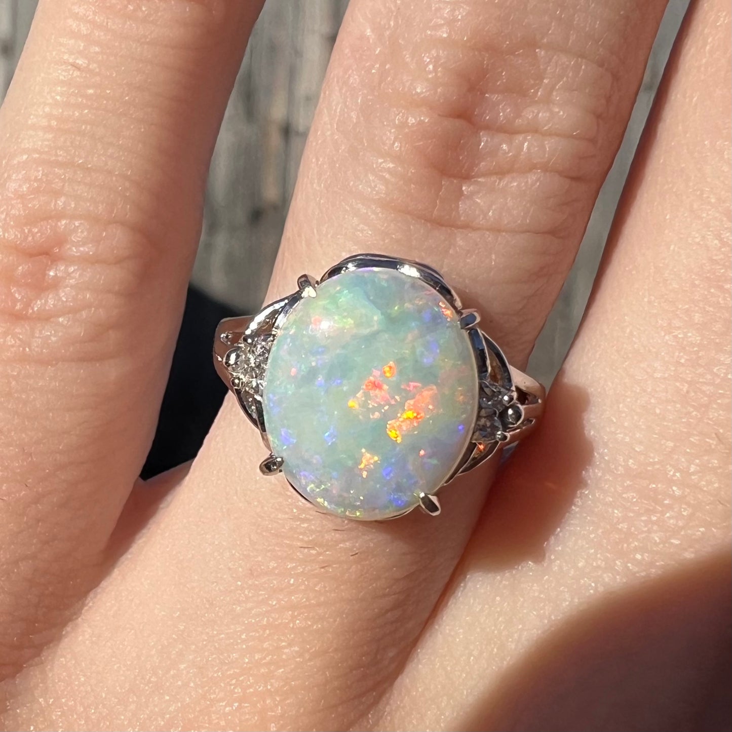 A 2.36ct opal platinum ring worn on a finger in the sunlight. 