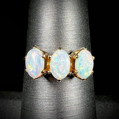 A vintage yellow gold ring mounted with three oval cut white Australian opals.