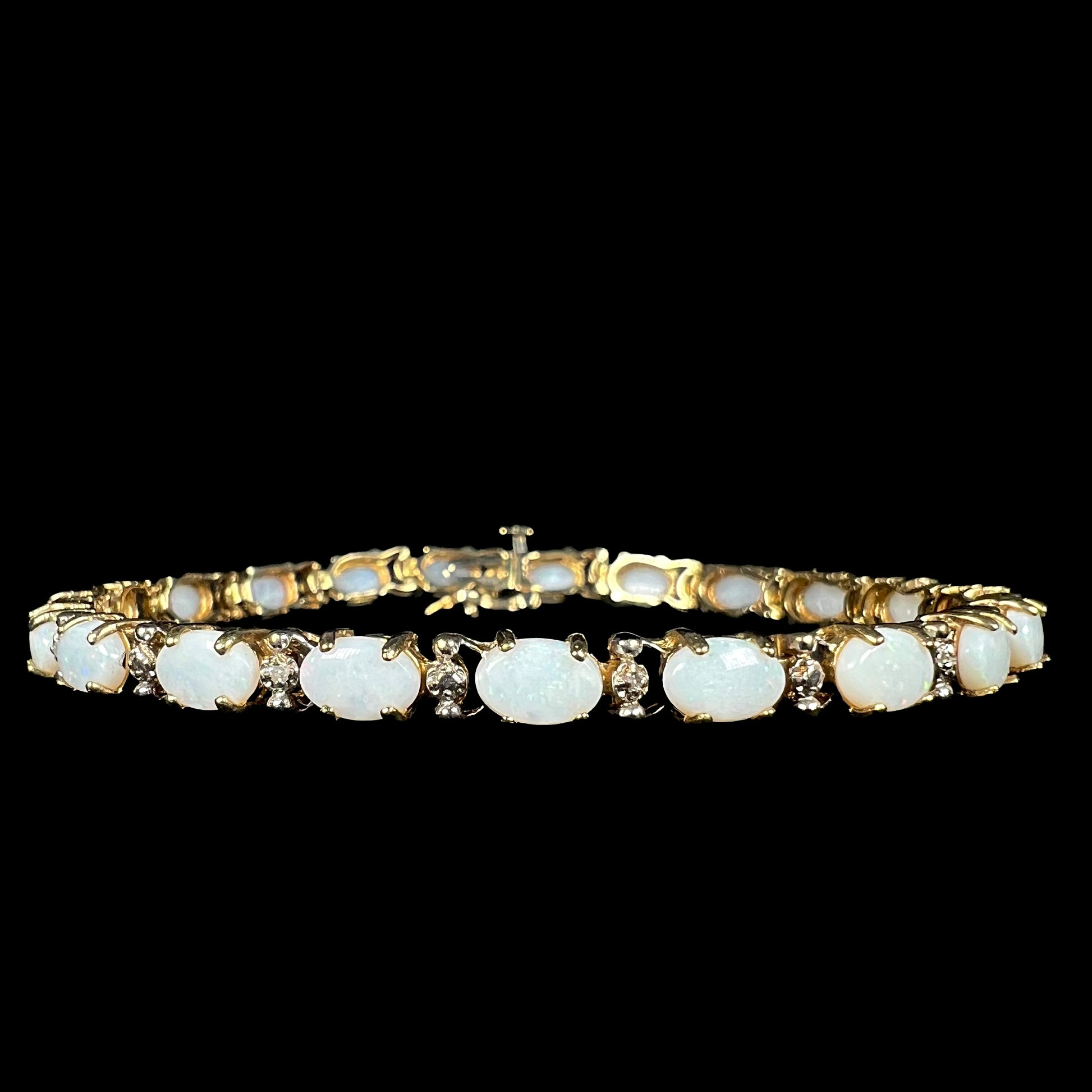 A 7 inch-long Australian white opal and diamond tennis bracelet in 10k gold shown from the front on a black background.
